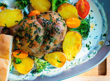 chicken baked in cream with potatoes, broccoli and cherry tomatoes in a metal baking dishの写真素材