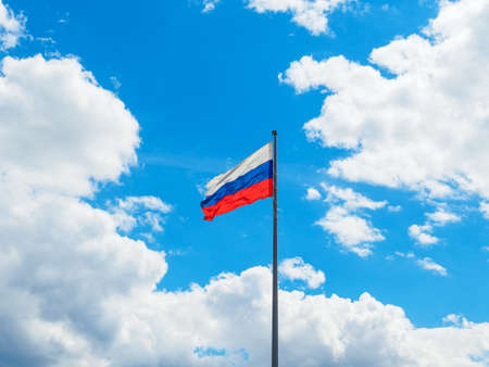 state flag of the Russian Federation against the background of blue sky and white cloudsの写真素材