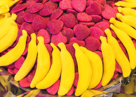 A lot of sugar jelly in the form of red hearts and bananas on the showcase of a pastry shopの写真素材