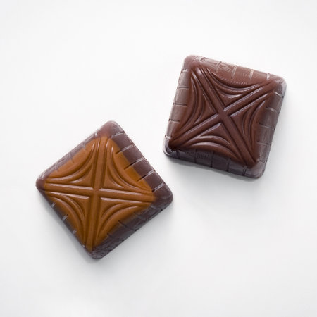 2 square candies made of milk and dark chocolate on a white backgroundの写真素材