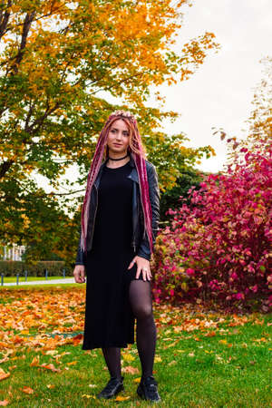 beautiful woman with long hair in black clothes in the autumn park. Full-length portraitの写真素材
