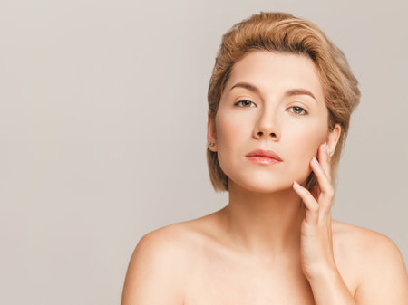 beautiful blonde with a short haircut and green eyes looks at the camera. Hand near the face. Without strapless.の写真素材