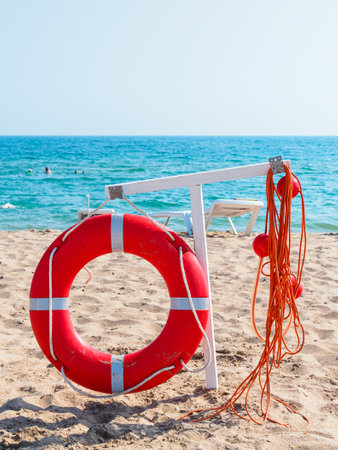 Red lifebuoy on the beach against the background of the sea close-up. Water safety conceptの写真素材