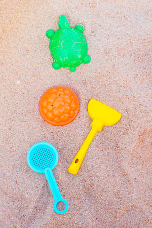 children's toys on the sand: molds - a flower and a turtle, a rake and a sieve. The concept of kids beach fun and sandbox gamesの写真素材