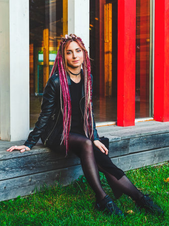 attractive woman with long pink and beige dreadlocks in black clothes outdoorsの写真素材