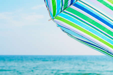 striped colorful beach umbrella against sea and sky backgroundの写真素材