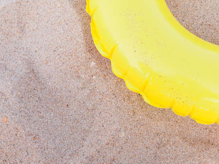 Yellow inflatable children's circle for swimming on golden sand, copy space for text. The concept of kids beach recreation and safety at seaの写真素材
