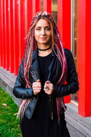 medium-plan portrait of a beautiful model with long pink dreadlocks in black clothes. Attractive woman looking at the cameraの写真素材