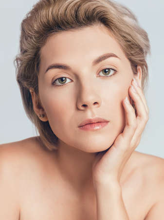 short-haired blonde with green eyes looking at the camera. Hand near faceの写真素材