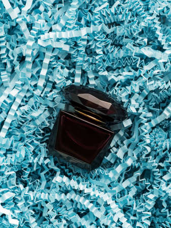 miniature of perfume in a dark bottle in an aroma box on blue wrapping paperの写真素材