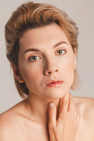 close-up portrait of a beautiful blonde girl with green eyes on a beige background in the studio.の写真素材