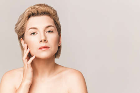 beautiful blonde with a short haircut and green eyes looks at the camera. Hand near the face. Without strapless.の写真素材