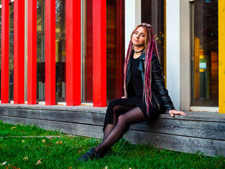 attractive woman with long pink and beige dreadlocks in black clothes outdoorsの写真素材