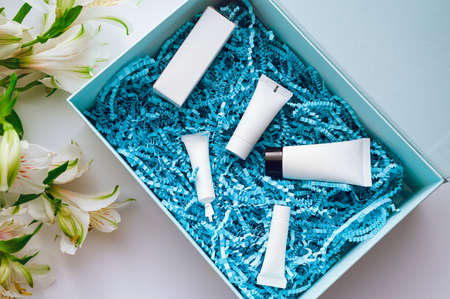 a set of samples of different cosmetics for face and body care in a box with blue shavings. Online shopping beauty conceptの写真素材