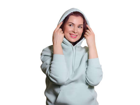 beautiful woman in a hoodie covers her head with a hood and smiles. Studio shot, medium shot, isolated on whiteの写真素材