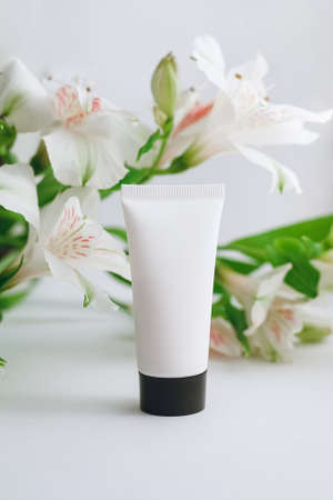 tube of moisturizer and alstroemeria on a white background close-upの写真素材