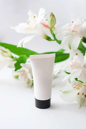 moisturizing hand cream in a white case with a black lid on a background of alstroemeriaの写真素材