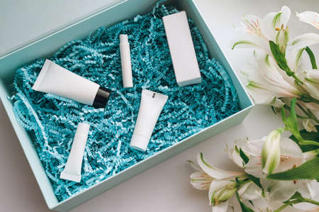 package with cosmetics: mask, moisturizer, serum, perfume, eye cream in blue wrapping paper shavingsの写真素材