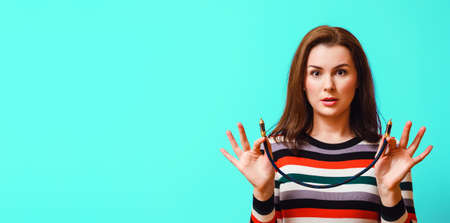 young attractive woman is surprised and holds a digital audio coaxial cable in her hands.の写真素材