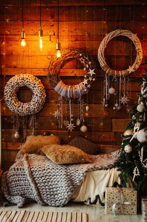 a place to relax, decorated to celebrate the New Year and Christmas: a sofa, wreaths on the walls, garlands and a blanket. Home festive atmosphereの写真素材