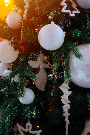 beautiful white toys and lights on the christmas tree in the eveningの写真素材