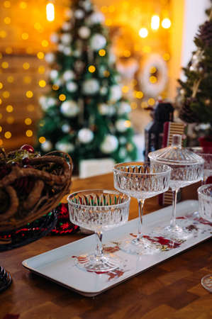 crystal glasses for sparkling wine on a white tray, Christmas tree on the background. The atmosphere of the New Year's celebrationの写真素材