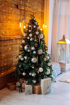 Christmas tree decorated with white toys in the living room, garland on the wooden wallの写真素材