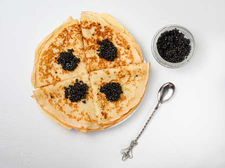 thin Russian pancakes with natural black caviar on a white plateの写真素材