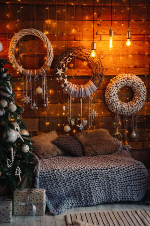 handmade wreaths decorated wooden wall, seating area and Christmas treeの写真素材