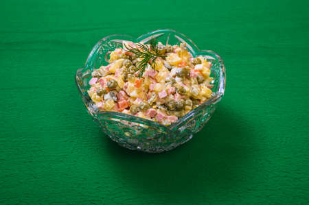 traditional russian new year salad olivier in vintage crystal vase on textured green backgroundの写真素材