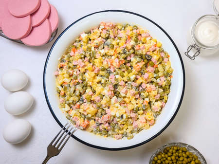 Russian festive salad Olivier in large enamel bowl on white background - flatlayの写真素材