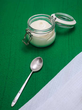 homemade mayonnaise in glass jar and spoon on green backgroundの写真素材