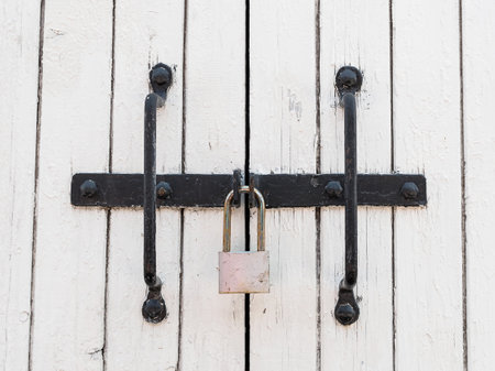 old metal padlock on white wooden gateの写真素材