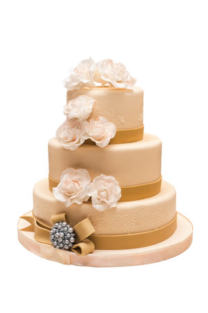 beautiful wedding cake with beige fondant, decorated with cream roses, ribbons and beads. isolated on whiteの写真素材