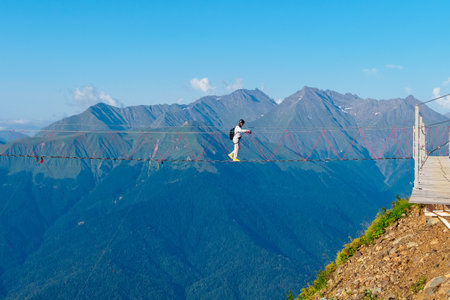 Sochi, Russia - August 24, 2022: Extreme entertainment in the mountains - walking on a suspension bridge in the Rosa Khutor Ski Complexのeditorial素材