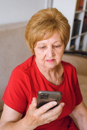 cute elderly woman looking at smartphone screenの写真素材