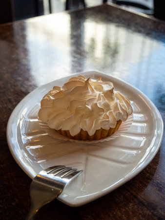 dessert in the cafe - lemon tartlets with meringue on a white plate and forkの写真素材