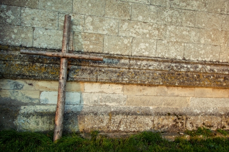 Wooden cross with stone wall background with grassの写真素材