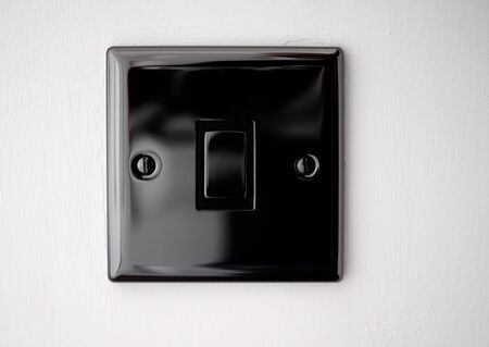 Black house hold light switch on a white wall