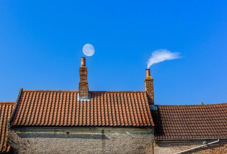 chimney roof line with moon and smokeの写真素材