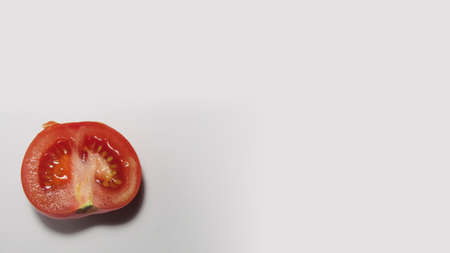 Red cut tomato on a white table. Ripe, juicy and appetizing vegetable.の写真素材