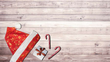 Christmas background. Red Santa Claus hat, gift and candy on a wooden table.