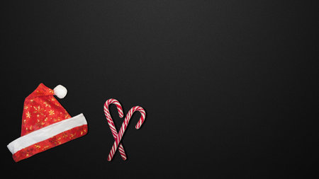 Black background. Santa Claus hat. Red Christmas hat and candies on a black background.