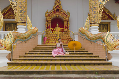 Architectural details wood carvings with a Girl in traditional Thai costume at Buddhist temple in Chiang Maiの写真素材