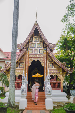 Girl with umbrella entering an old Buddhist temple in Chiang Maiの写真素材