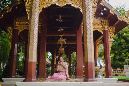 South Asian model in Thai costume sitting inside a Buddhist temple landmark in Chiang Mai