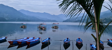 Panorama of Blue boats before the idyllic Himalayan sunset of Phewa lake in Pokharaの写真素材