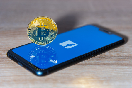 Bitcoin coin with the Facebook logo screen backgroundのeditorial素材