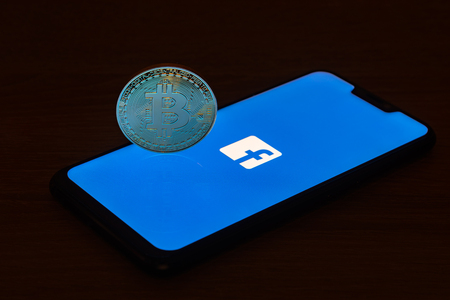 Bitcoin coin with the Facebook logo screen backgroundのeditorial素材