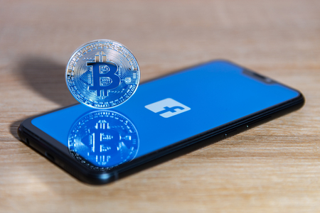 Bitcoin coin with the Facebook logo screen backgroundのeditorial素材